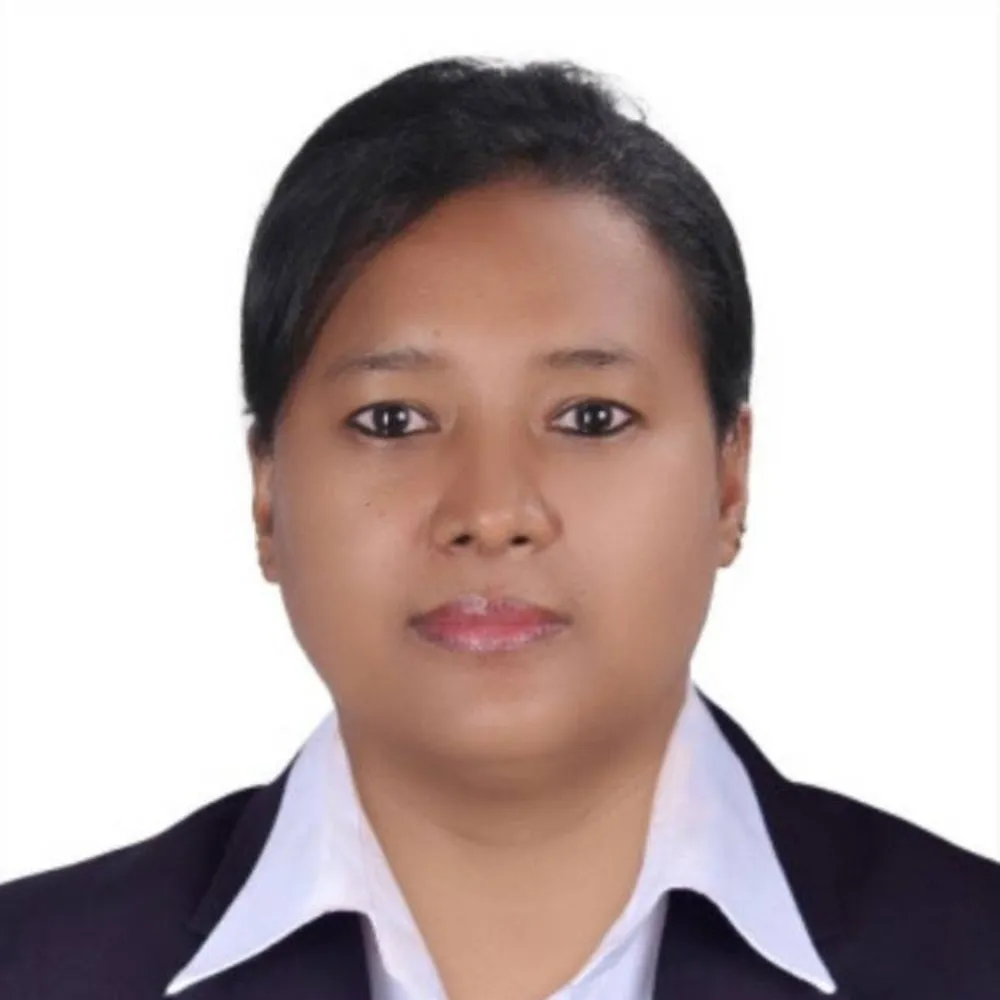 Portrait of a person with short dark hair, wearing a white collared shirt and dark blazer against a plain white background, conveying a professional demeanor.